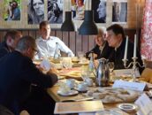 Personen diskutieren bei einem Pressegespräch am Schlosscampus, umgeben von Fotos und gedecktem Tisch.