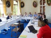 Eine Gruppe von Menschen sitzt bei einem Pressegespräch in einem eleganten Raum am Schlosscampus an einem Tisch.