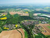 Luftaufnahme von Jagsthausen zeigt ein malerisches Dorf umgeben von grünen Feldern und Wäldern in einer ländlichen Landschaft.