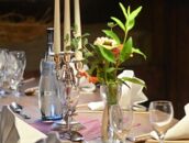 Ein elegant gedeckter Tisch mit Kerzenleuchter und Blumenstrauß schafft eine einladende Atmosphäre auf dem Schlosscampus.